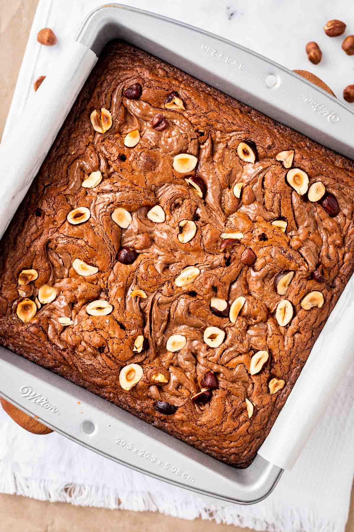 A baking pan full of brownies sprinkled with hazelnuts.