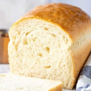 White bread with the first slice cut off next to a white and blue dish towel