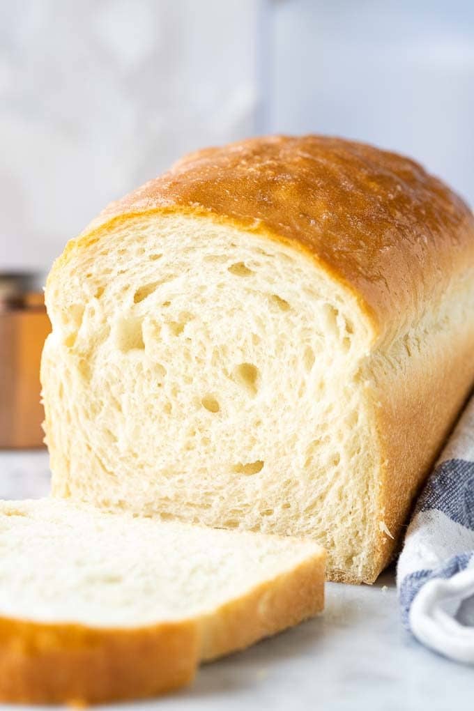 White bread with the first slice cut off next to a white and blue dish towel