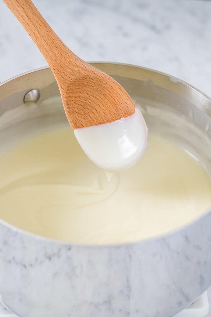 Coconut Cream Pie filling in a pot with a wooden cooking spoon
