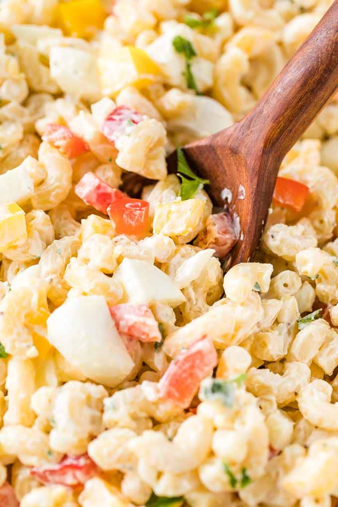 Close-up of Macaroni Salad with a wooden spoon.