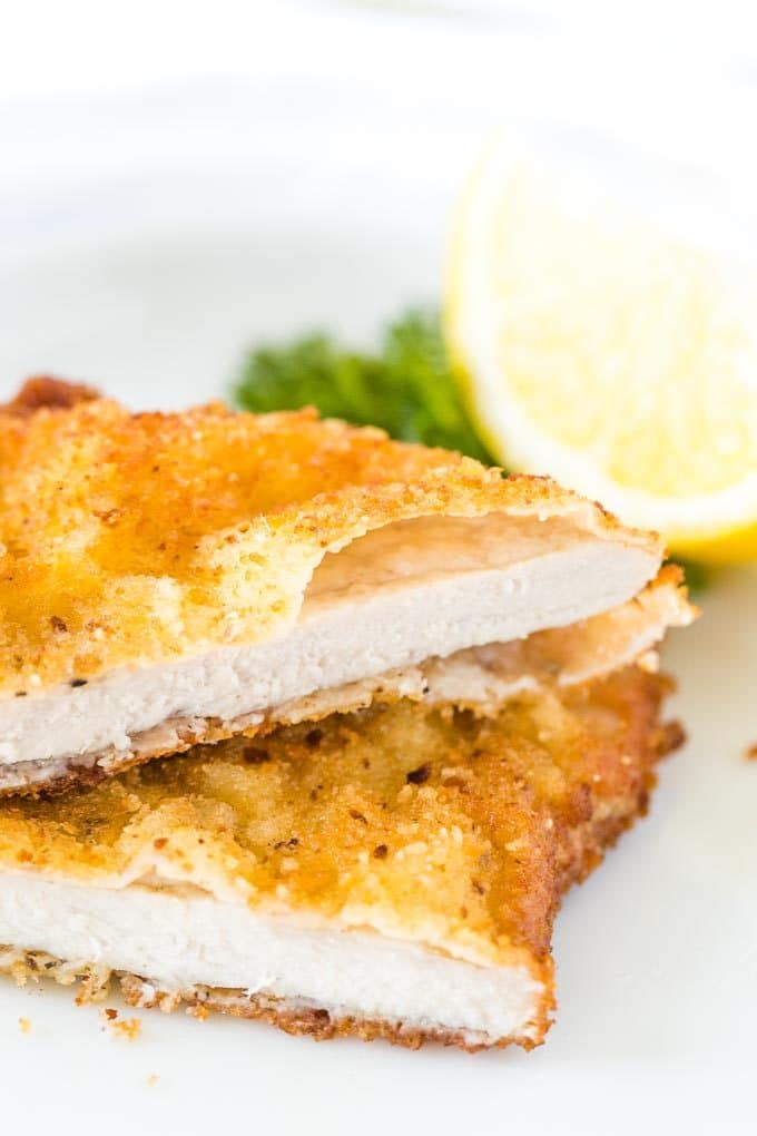 Schnitzel, cut in half, stacked on a plate, garnished with lemon and parsley