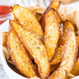 Air Fryer Potato Wedges in a white bowl, garnished with Parmigiano