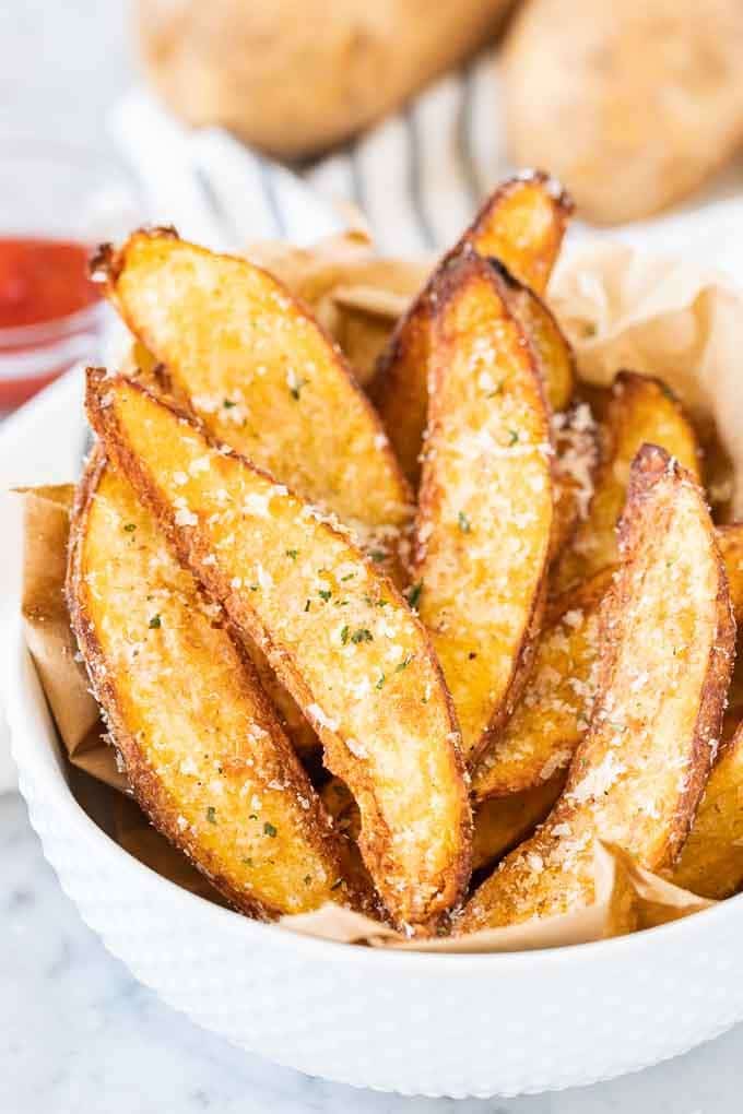 Air Fryer Potato Wedges in a white bowl, garnished with Parmigiano