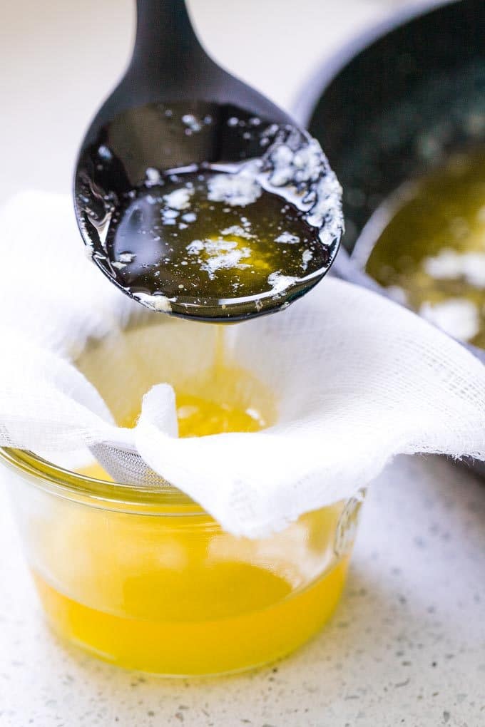Clarified Butter being strained through a cheese cloth into a glass jar.
