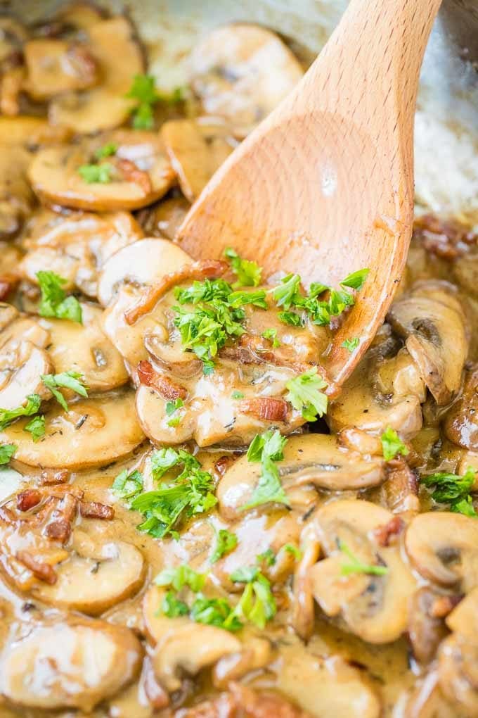 Mushroom bacon gravy for Jaegerschnitzel with a wooden cooking spoon