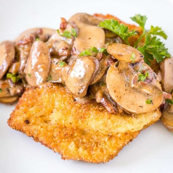 Schnitzel topped with Mushroom, bacon gravy, garnished with parsley