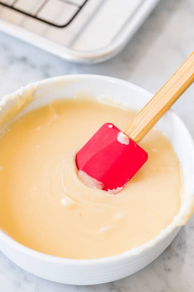 Air Fryer Donut Glaze in a white bowl with a red spatula