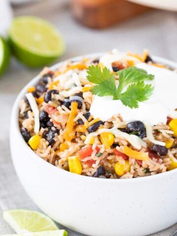 Black Beans and Rice in a bowl, topped with cheese and sour cream