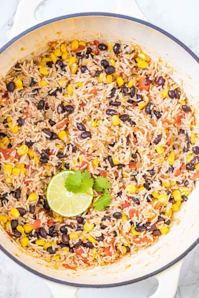 Rice and Beans in a white pan, garnished with a slice of lime and cilantro