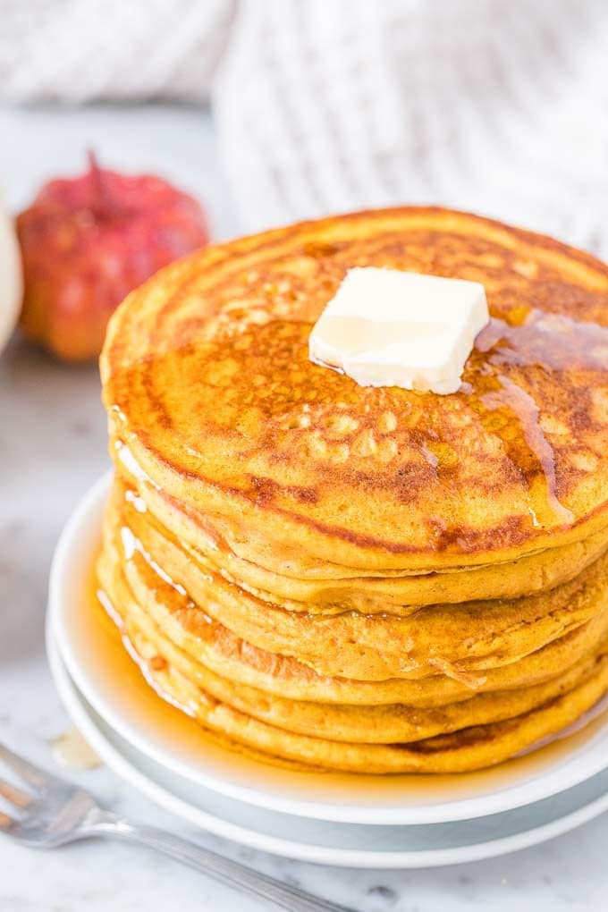A stack of Pumpkin Pancakes topped with butter and Maple Syrup