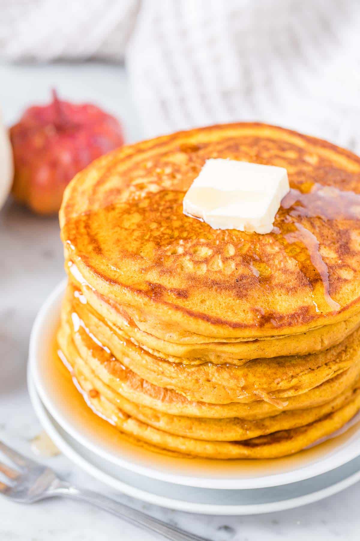 A stack of Pumpkin Pancakes topped with butter and Maple Syrup.
