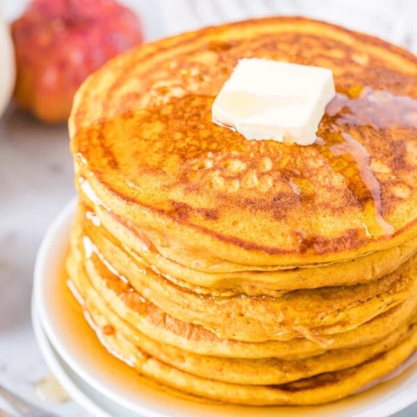 A stack of Pumpkin Pancakes topped with butter and Maple Syrup.
