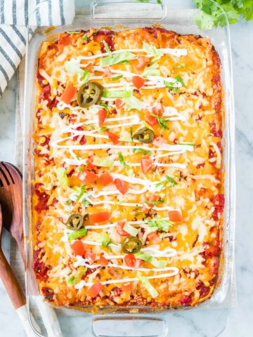 Taco Lasagna in a glass baking dish topped with sour cream