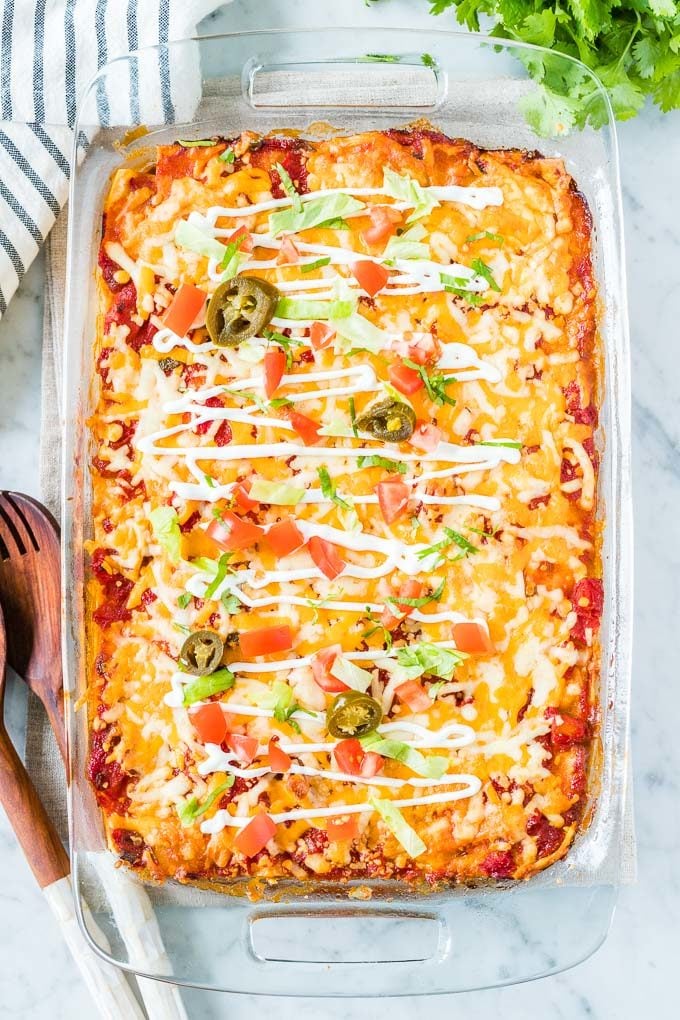 Taco Lasagna in a glass baking dish topped with sour cream