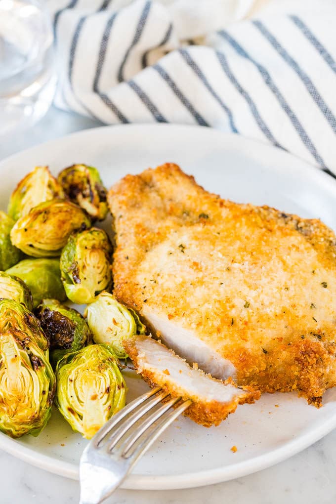 Breaded pork chops on a plate with brussels sprouts