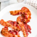 Crispy Bacon on a plate next to an Air Fryer