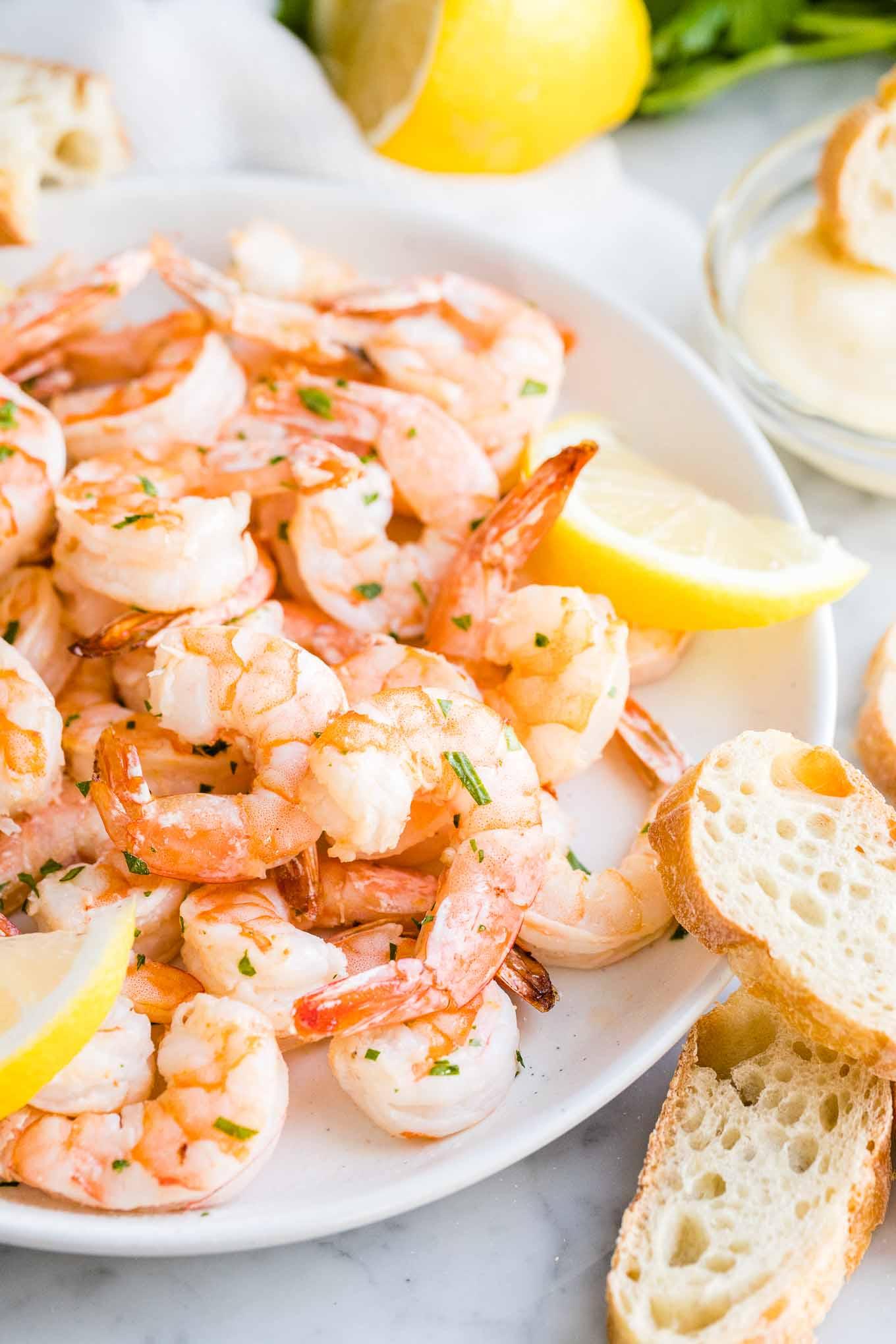 Air Fryer Shrimp on a plate with bread on the side garnished with Lemon slices.