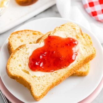 Two slices of bread on a plate with butter and jam spread on top