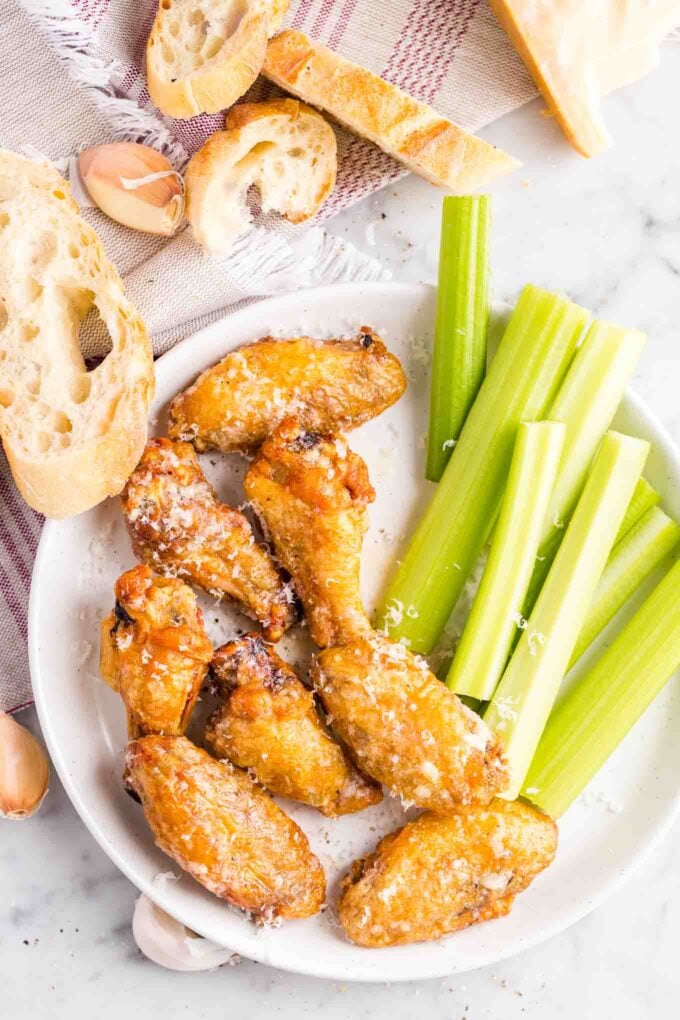 Chicken Wings and celery sticks on a plate with bread slices on the side