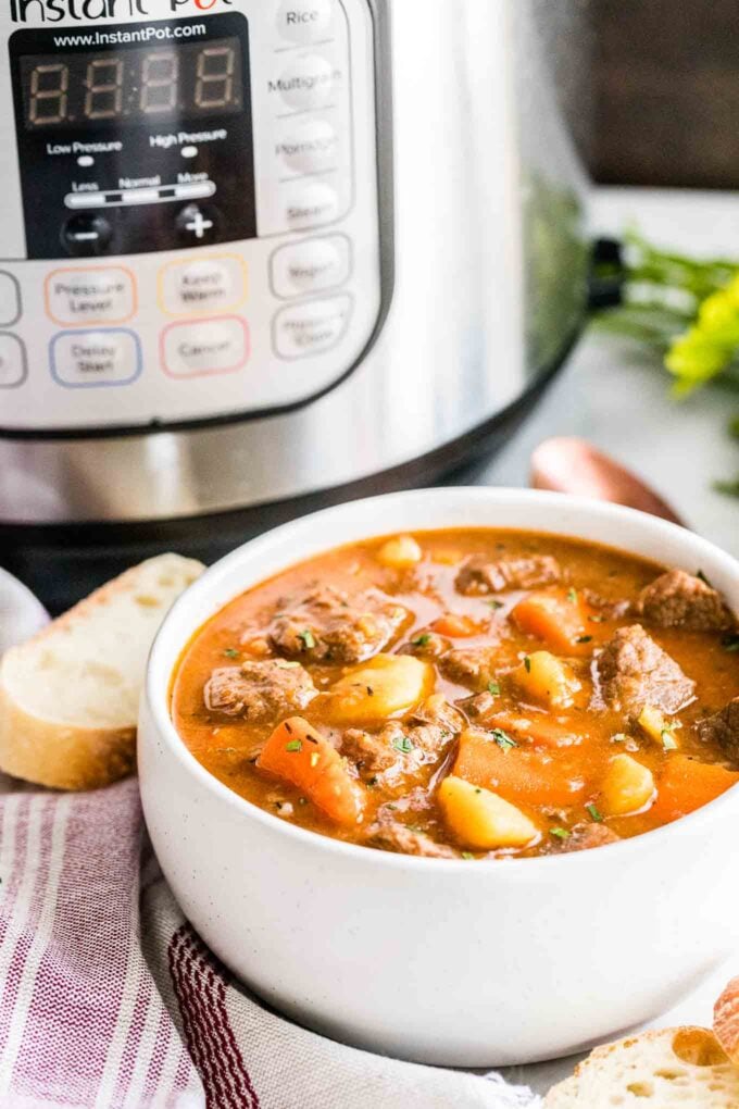 A bowl of beef stew next to an Instant Pot