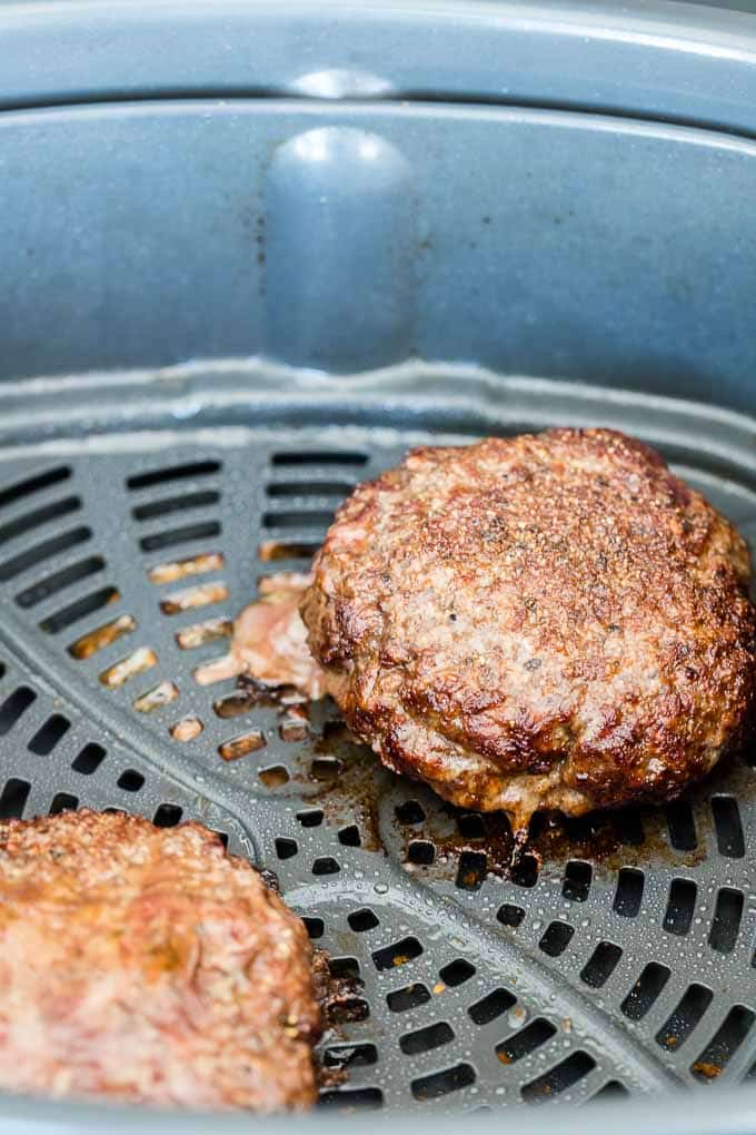 Two cooked hamburger patties in the Air Fryer basket