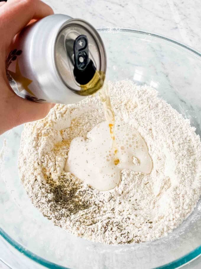 Pouring beer into a bowl filled with flour