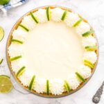 A key lime pie decorated with whipped cream and lime slices