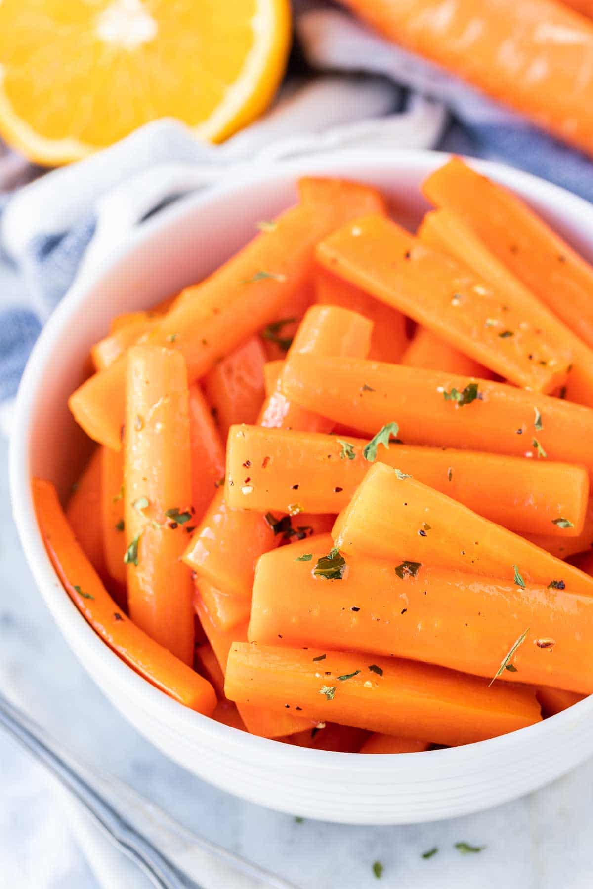 Glazed Carrots in a serving bowl with an orange next to it