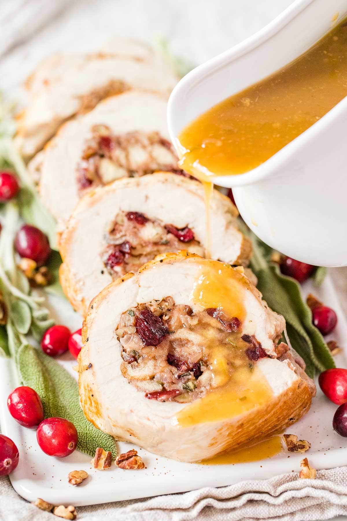Sliced stuffed turkey breast on a serving plate drizzled with gravy