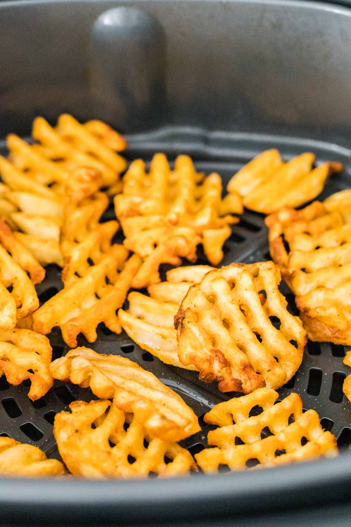 Waffle fries in an air fryer basket
