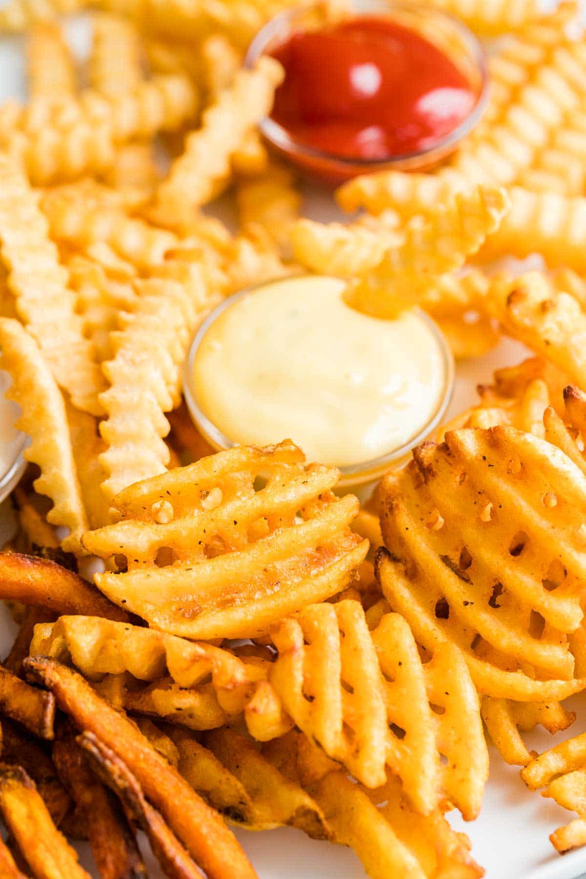 Close up of air fried french fries with a side of mayonnaise and ketchup