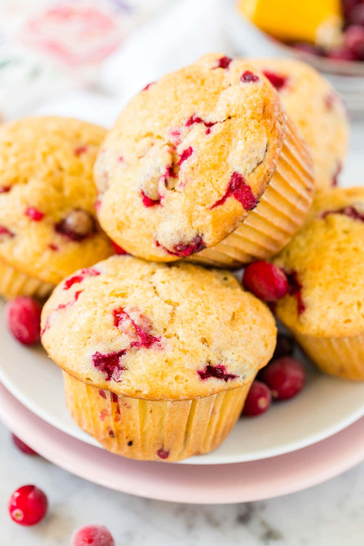 A stack of orange cranberry muffins on a white plate