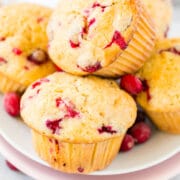 A stack of orange cranberry muffins on a white plate.