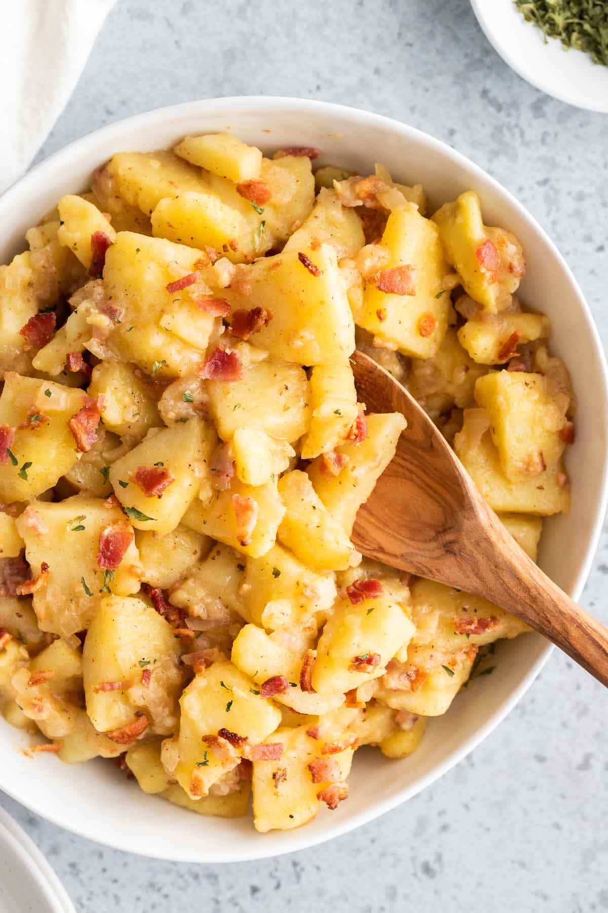 German potato salad in a serving bowl with a spoon sticking out