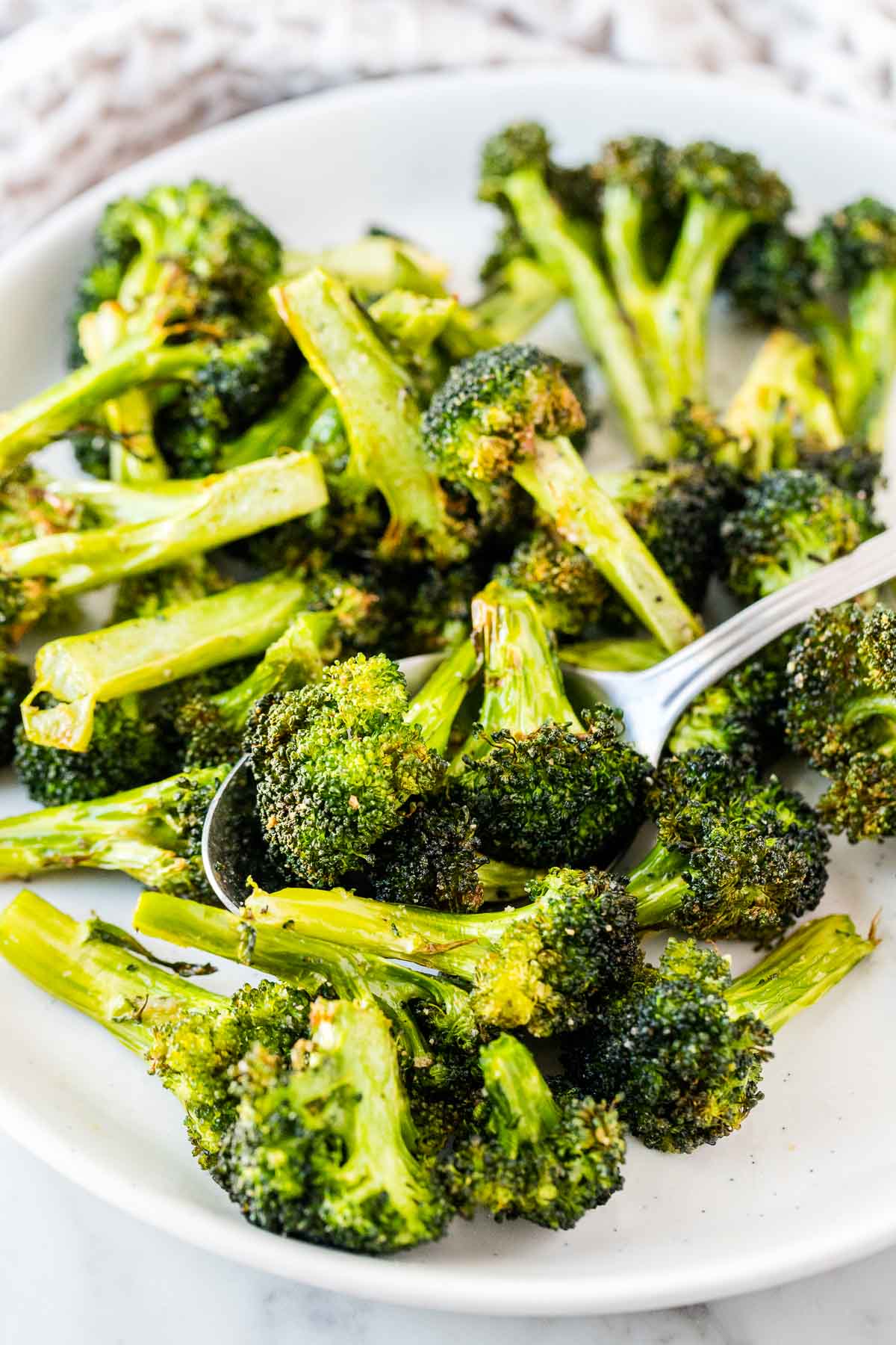 Broccoli florets on a plate with a serving spoon