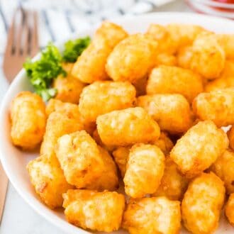 Air Fried Tater Tots on a white plate next to a small bowl of ketchup