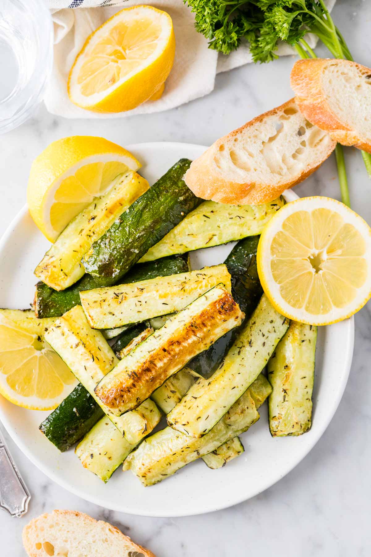 Roasted Zucchini on a white plate garnished with lemon slices