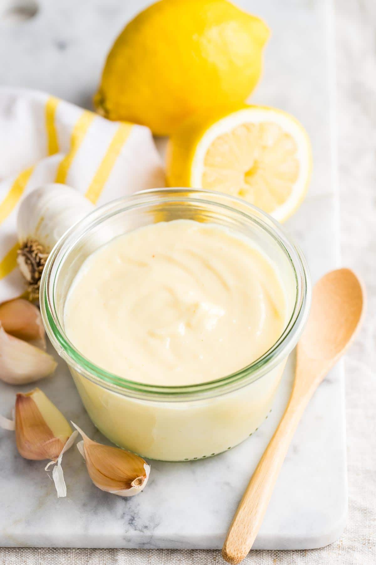 Aioli sauce in a glass jar on a marble board