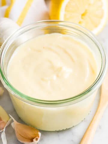 Aioli sauce in a glass jar on a marble board