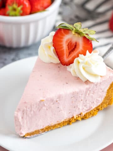 A slice of Strawberry Cheesecake on a white plate