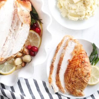 Sliced turkey breast on a plate next to a bowl of mashed potato and a whole turkey breast