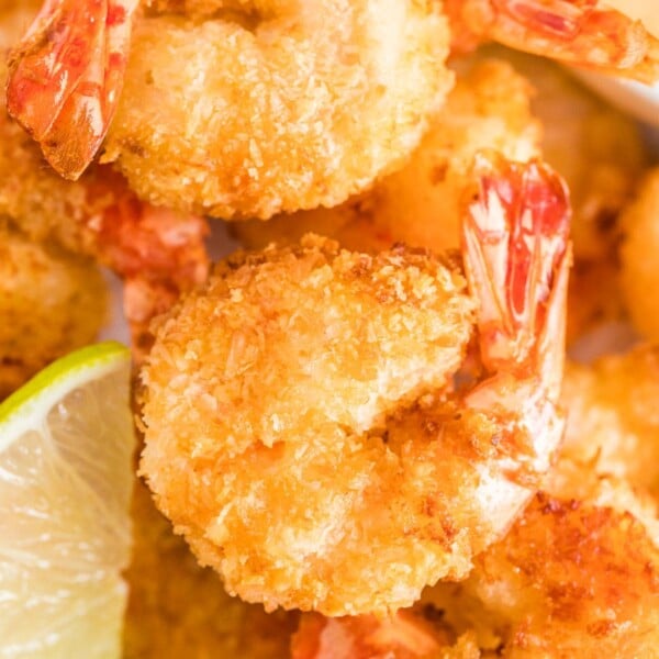 A close up of air-fried coconut shrimps next to a slice of lime.