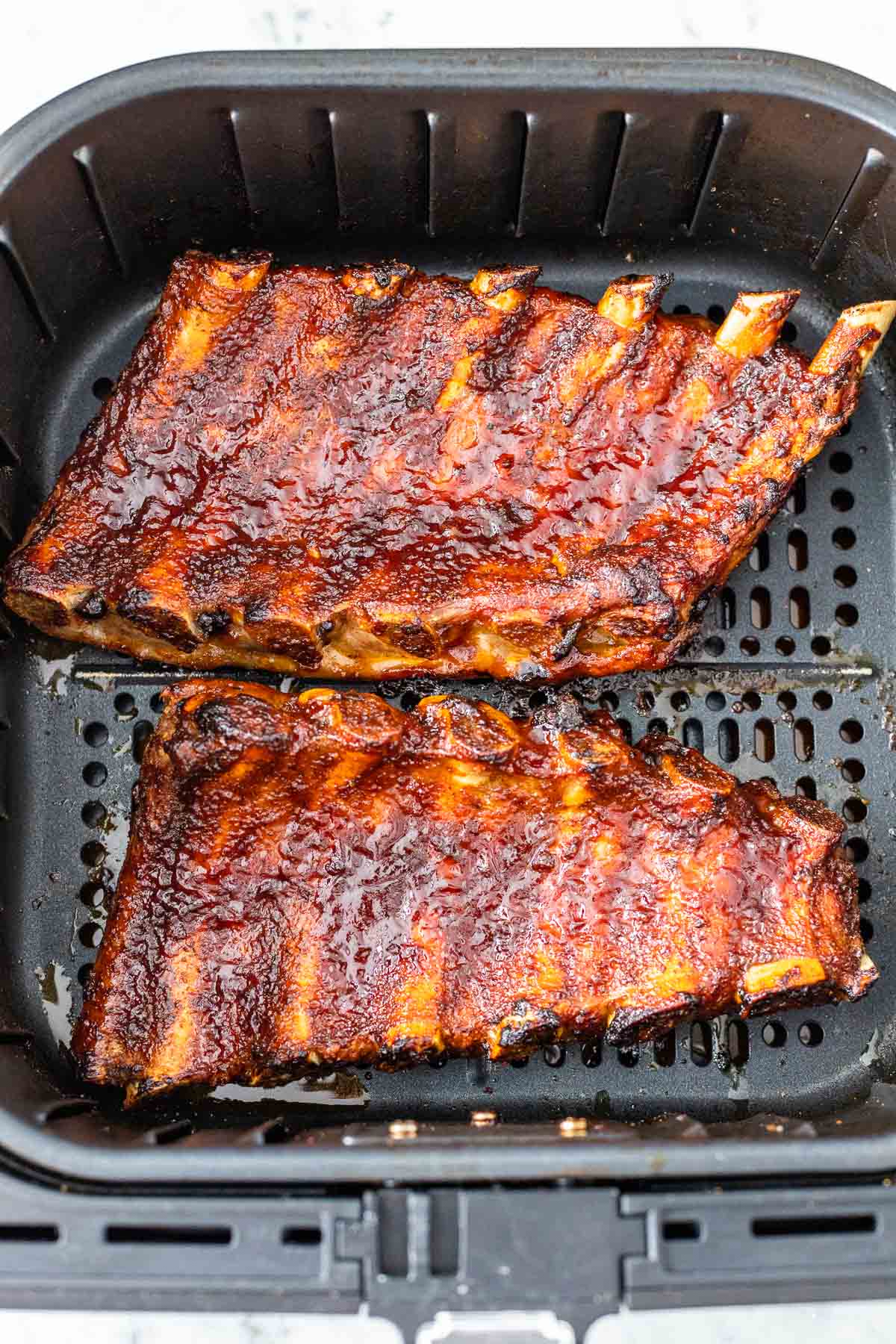 A cooked rack of ribs in an air fryer basket
