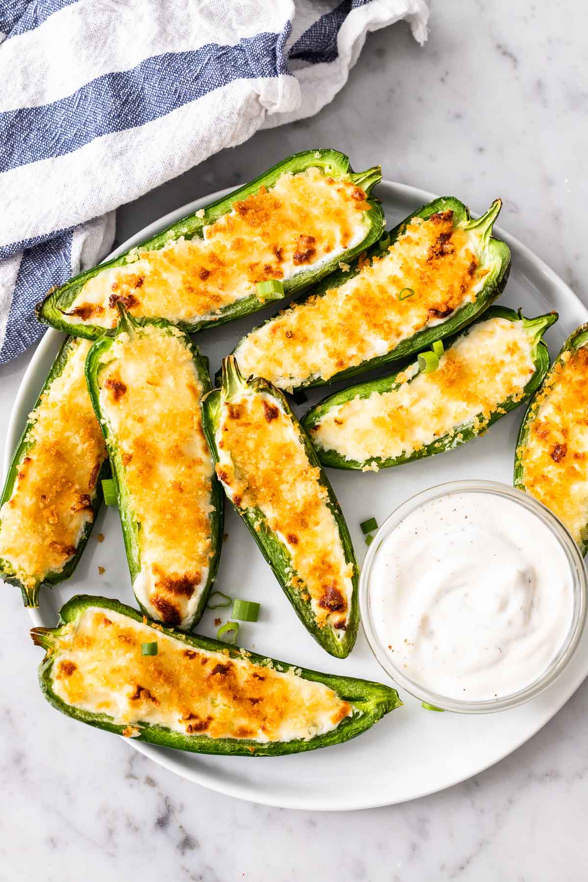 Jalapeno Poppers arranged on a white plate with a small bowl filled with a dip next to it