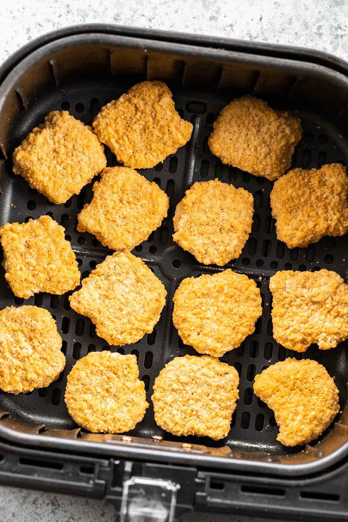 Frozen chicken nuggets in an Air Fryer basket.