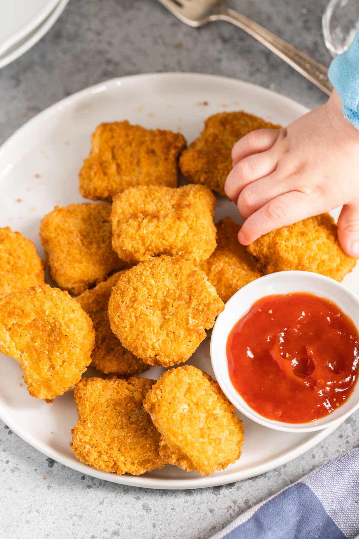 A toddler hand picking up a chicken nugget.