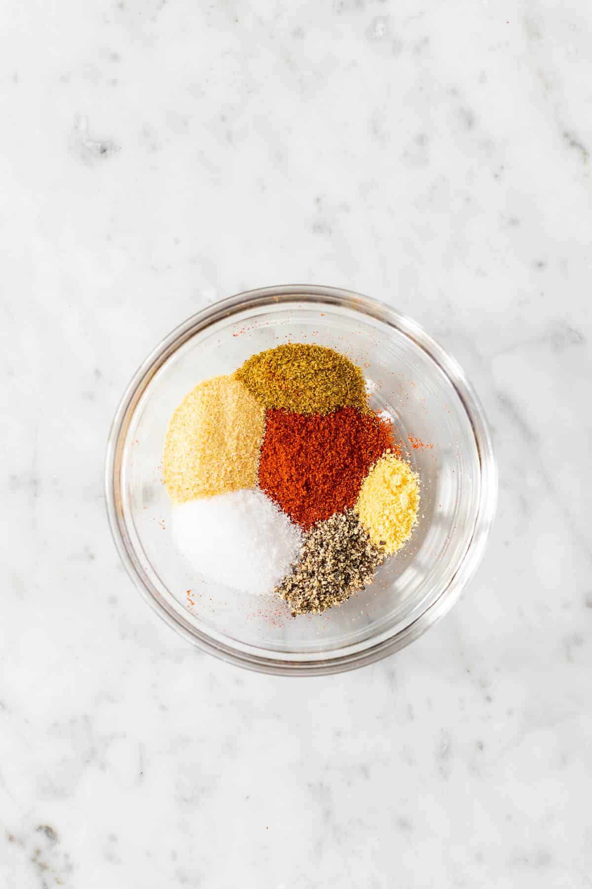 Different spices and seasonings in a small glass bowl.