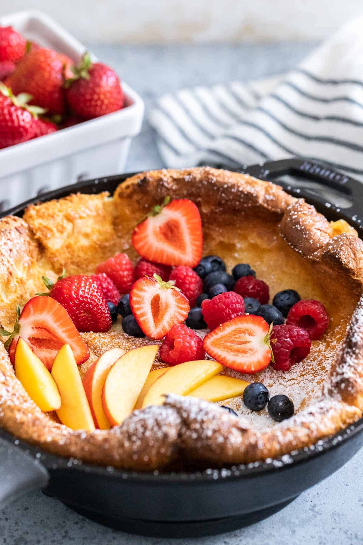 A Dutch Baby pancake in a cast iron pan garnished with berries.