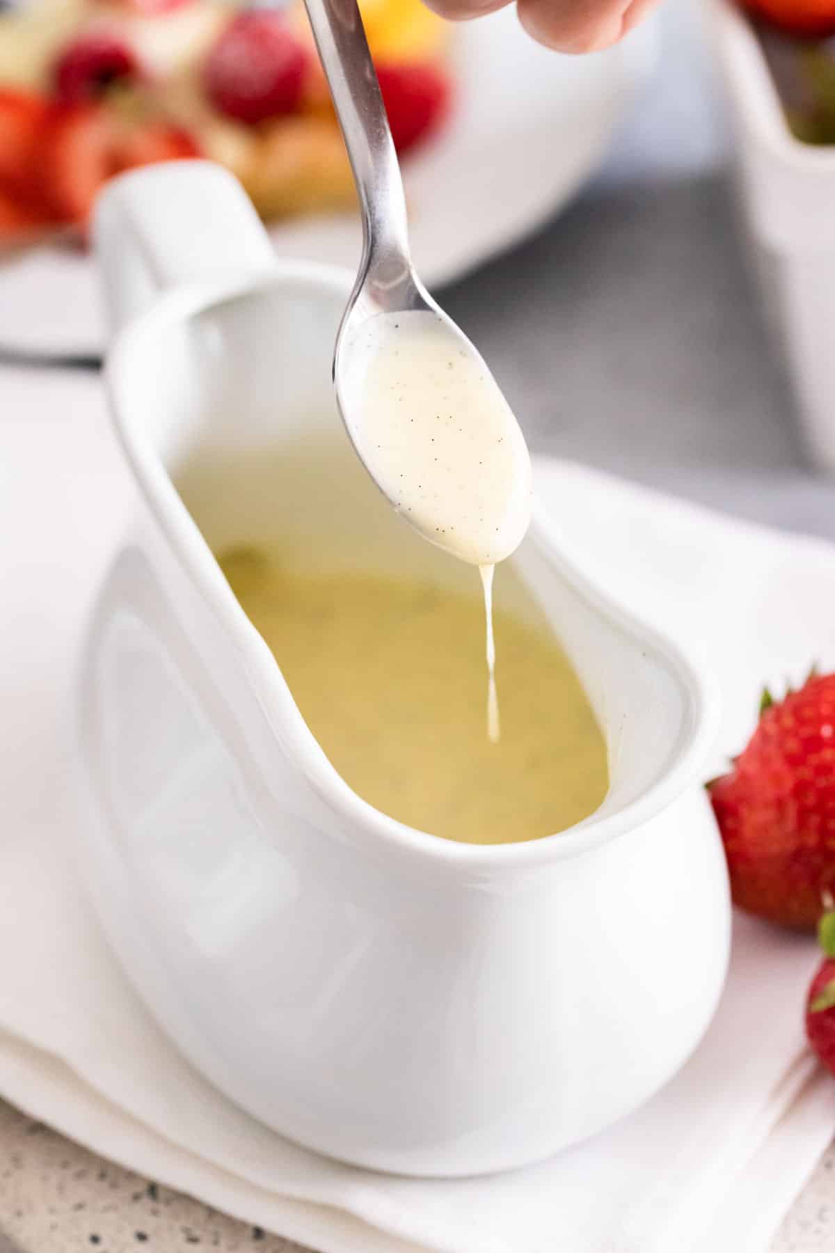 Vanilla sauce dripping from a spoon into a bowl.